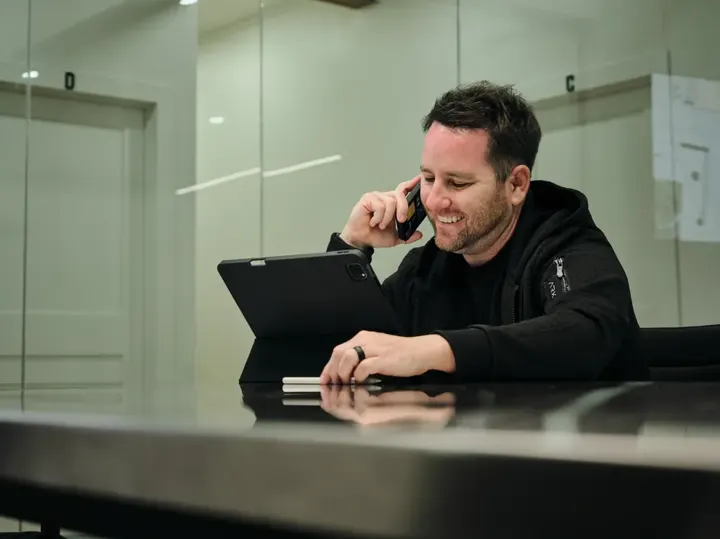 Team member on a phone call with a tablet at a desk