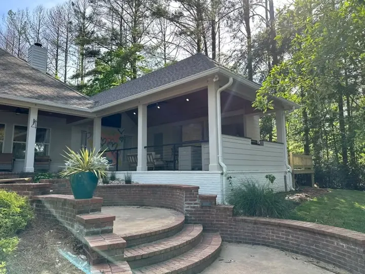 Brick patio steps curving beside a covered porch and flower pots