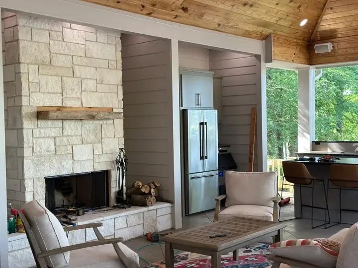 Covered outdoor living room with a stone fireplace and seating