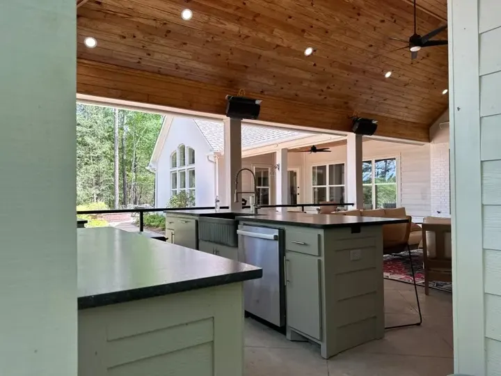 Outdoor kitchen island under a timber ceiling with views of the yard