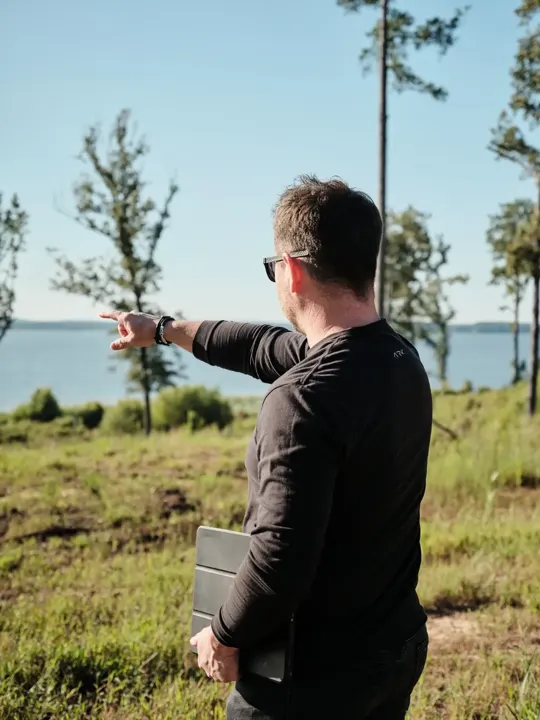 Team member pointing across open land toward a lake