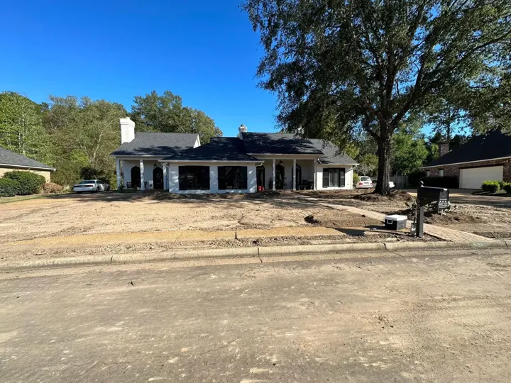 Front of a single story home with bare ground across the yard