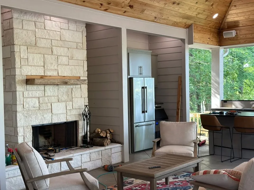 Covered outdoor living room with a stone fireplace and seating
