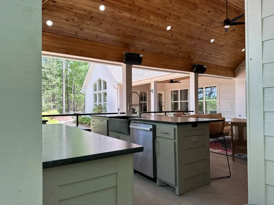 Outdoor kitchen island under a timber ceiling with views of the yard