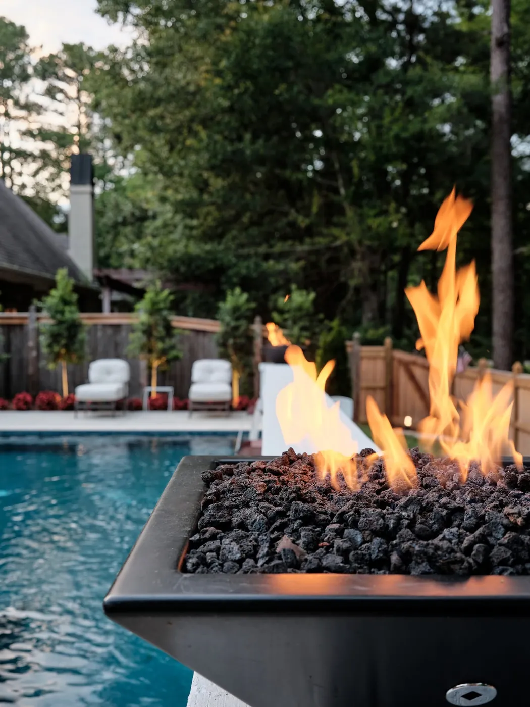 Fire bowl with flames beside a pool and outdoor seating